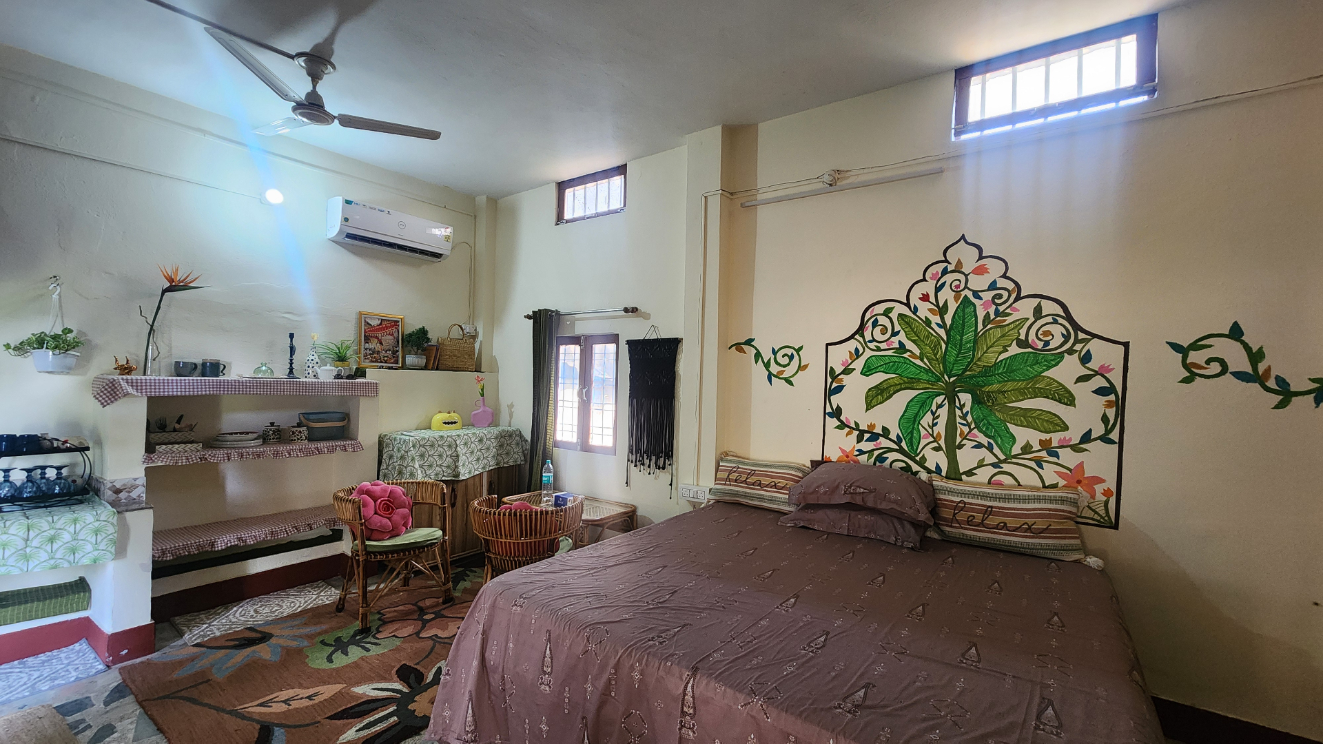 Spacious bedroom at Now & Nature with hand-painted floral mural and rattan furniture